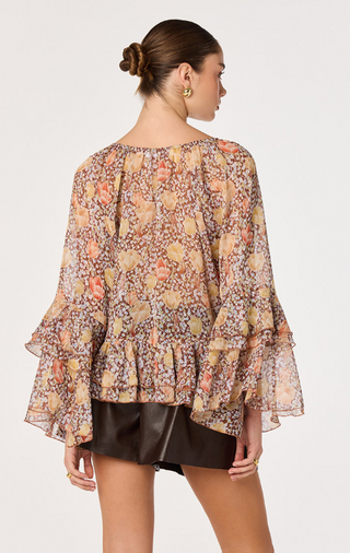 Make a statement in this beautifully romantic floral boho blouse, designed with effortless elegance and feminine charm. Featuring a vibrant allover floral print on lightweight, semi-sheer fabric, this flowy women's blouse is perfect for transitioning from season to season.

The dramatic tiered bell sleeves create graceful movement, while the adjustable self-tie neckline lets you wear it open or tied for versatile styling. A tiered ruffle high-low hem adds soft dimension and a flattering silhouette, making t
