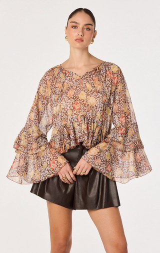 Make a statement in this beautifully romantic floral boho blouse, designed with effortless elegance and feminine charm. Featuring a vibrant allover floral print on lightweight, semi-sheer fabric, this flowy women's blouse is perfect for transitioning from season to season.

The dramatic tiered bell sleeves create graceful movement, while the adjustable self-tie neckline lets you wear it open or tied for versatile styling. A tiered ruffle high-low hem adds soft dimension and a flattering silhouette, making t