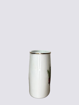 A tall white ceramic vase with a gold rim and a small side illustration, set against a neutral beige fabric backdrop.