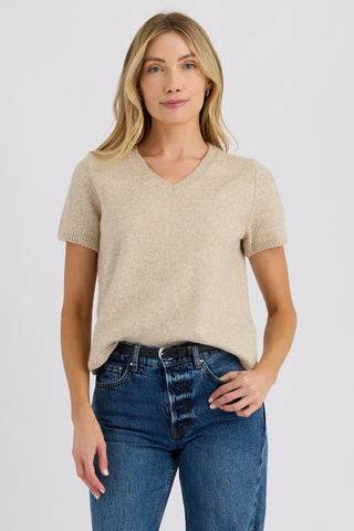 Woman wearing a beige sweater and blue jeans on a white background