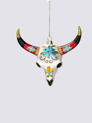 A decorative hanging ornament shaped like a white skull with long curved horns. The ornament is decorated with colorful floral and scroll patterns in blue, yellow, green, and purple, with black and red sections on the horns and gold accents.