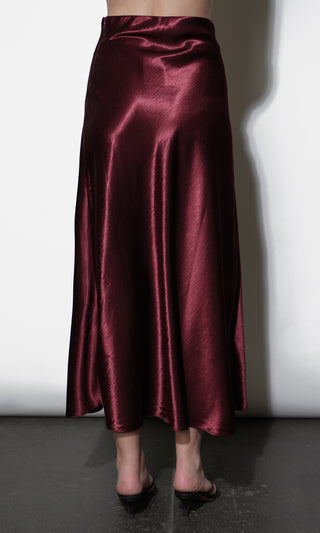 Burgundy satin skirt worn by a person on a white background