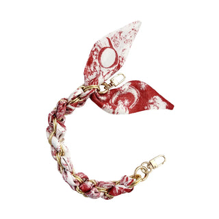 A braided chain bracelet with a red and white patterned scarf tied to it, featuring gold-tone metal hardware, shown on a plain white background.