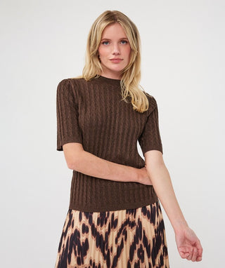 A woman modeling a brown short-sleeve ribbed knit top paired with a beige and black leopard print skirt, photographed against a plain light gray studio background.
