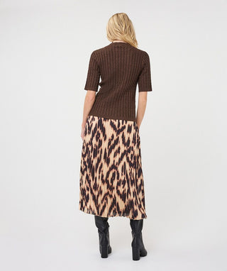A woman shown from the back wearing a brown ribbed short-sleeve top and a beige leopard-print midi skirt, paired with black ankle boots, against a plain light gray studio background.