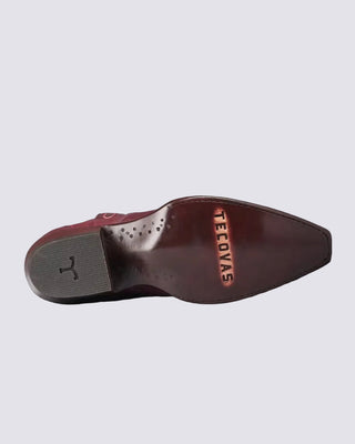 The underside of a brown leather shoe by TeeCovas, showing the branded insole and textured gray heel, photographed against a solid black background.