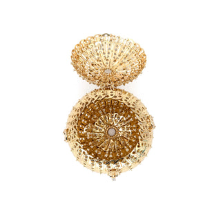 A gold-toned filigree jewelry box shown open against a plain white background, with an intricate circular pattern and a small light center detail.