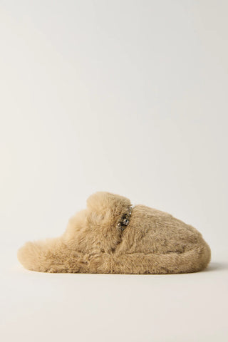 A single fluffy beige slipper with a small dark beaded decorative detail across the top, photographed against a clean, light off-white background.
